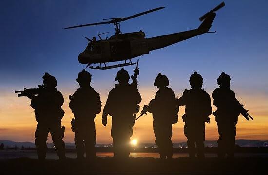 Silhouetted military team and helicopter at dusk